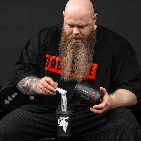 Man with long beard scooping Berserk EAAs powder into a shaker bottle for muscle building and hydration