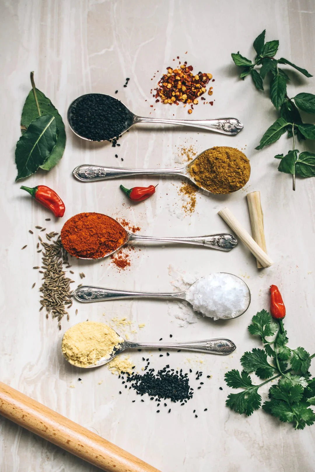 Various colorful spices and herbs arranged on silver spoons symbolizing antioxidants in sports nutrition