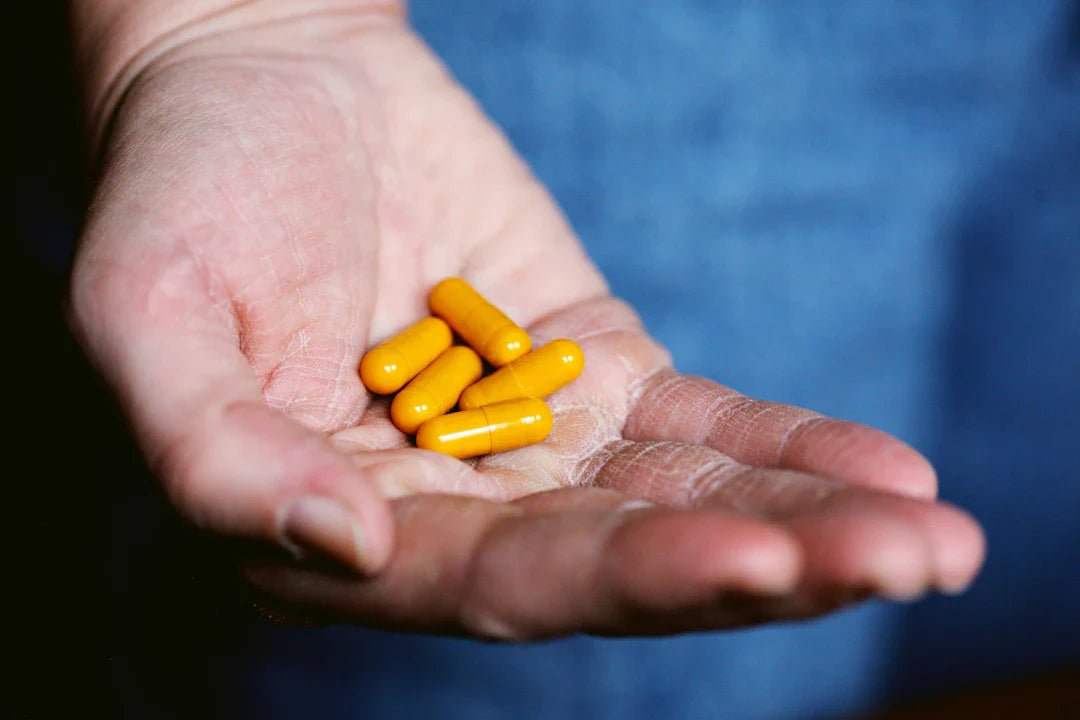 Hand holding yellow supplement capsules representing Nahrungsergänzungsmittel für Sportler