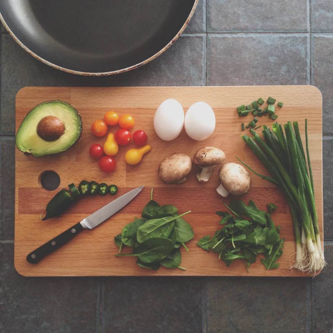 Chopped fresh vegetables, eggs, and herbs on a wooden cutting board for healthy sports nutrition and mental well-being