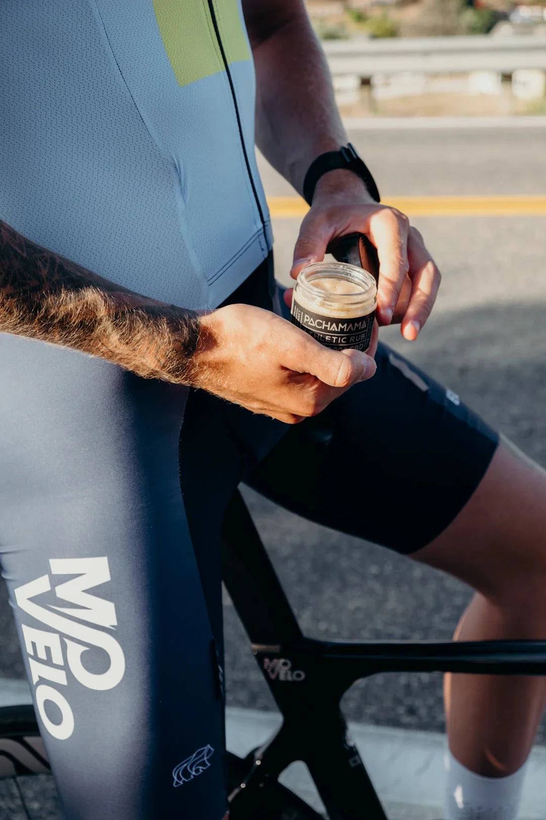 Athlete holding injury recovery supplement outdoors next to bicycle during verletzungsbedingte Pausen