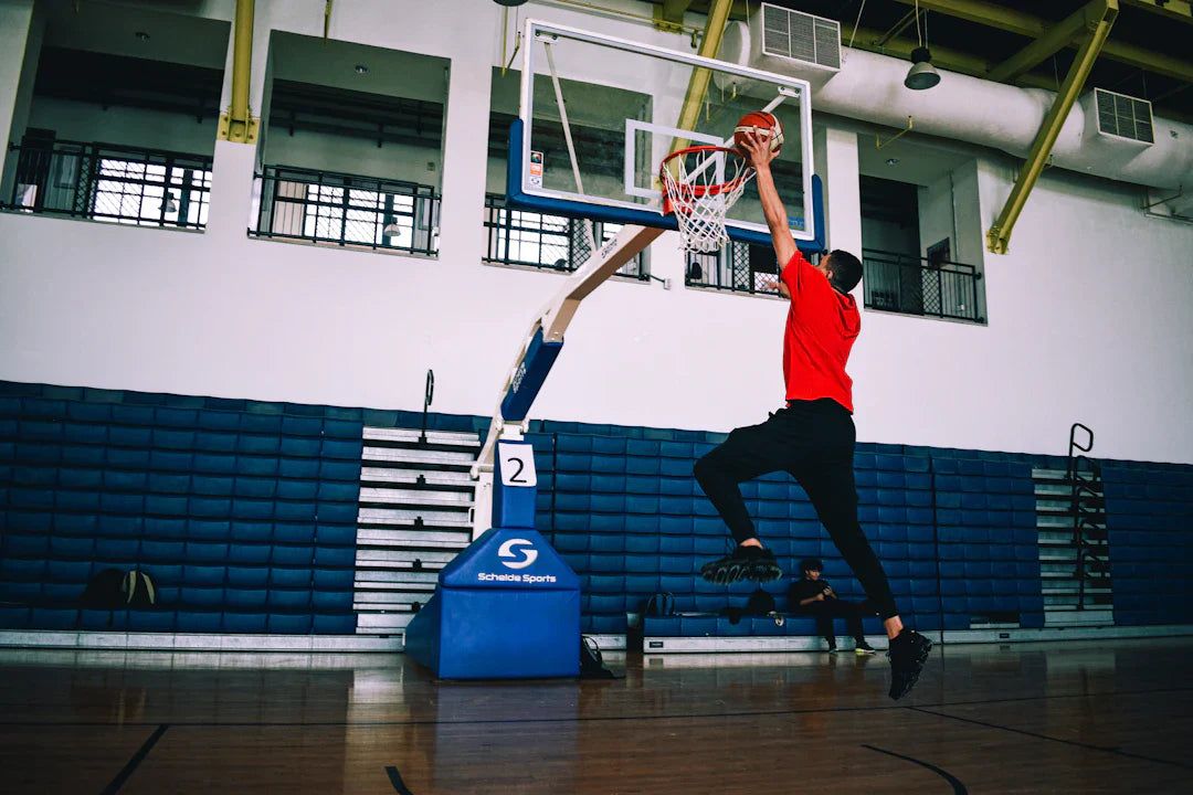 Athlete jumping to score a basketball in an indoor sports gym, highlighting benefits of phytonutrients for athletes.